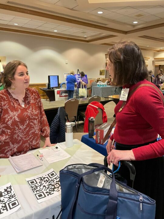 Allison speaking with conference attendee at booth
