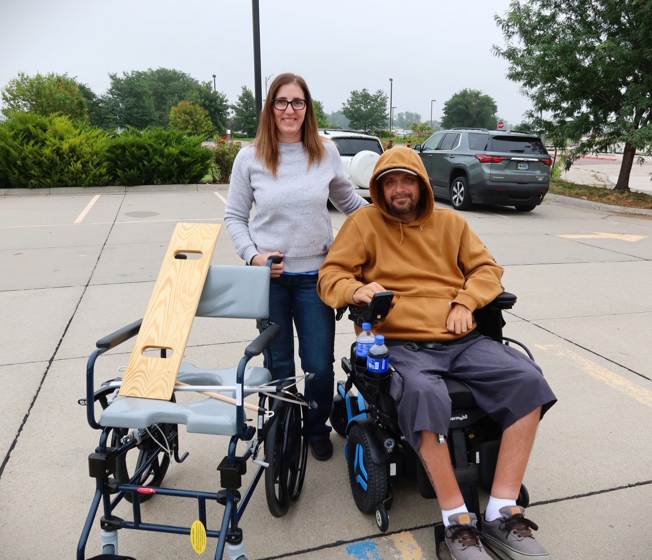 IMG_5847 a woman standing next to a man seated in a wheelchair